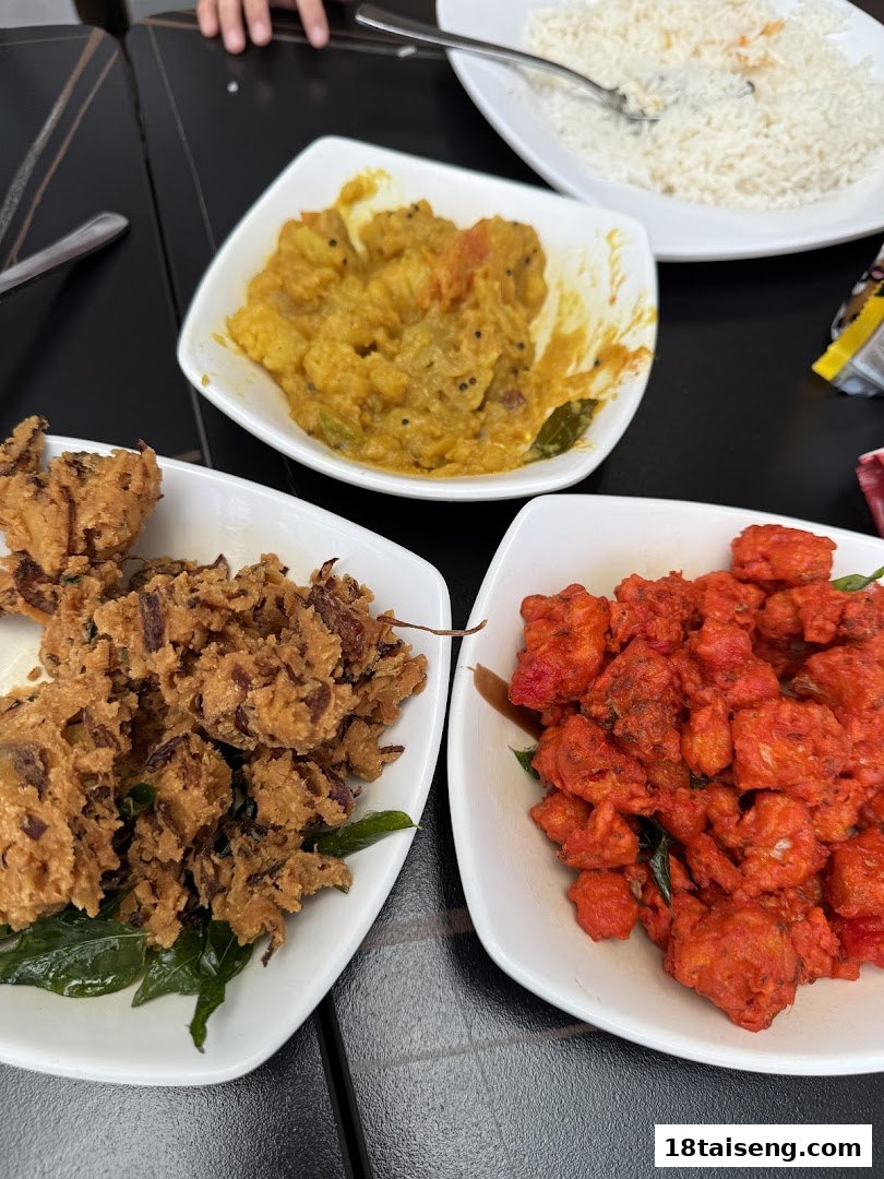 A table laden with vibrant Indian dishes: crispy fritters, spicy red chicken, and a yellow vegetable curry with rice.