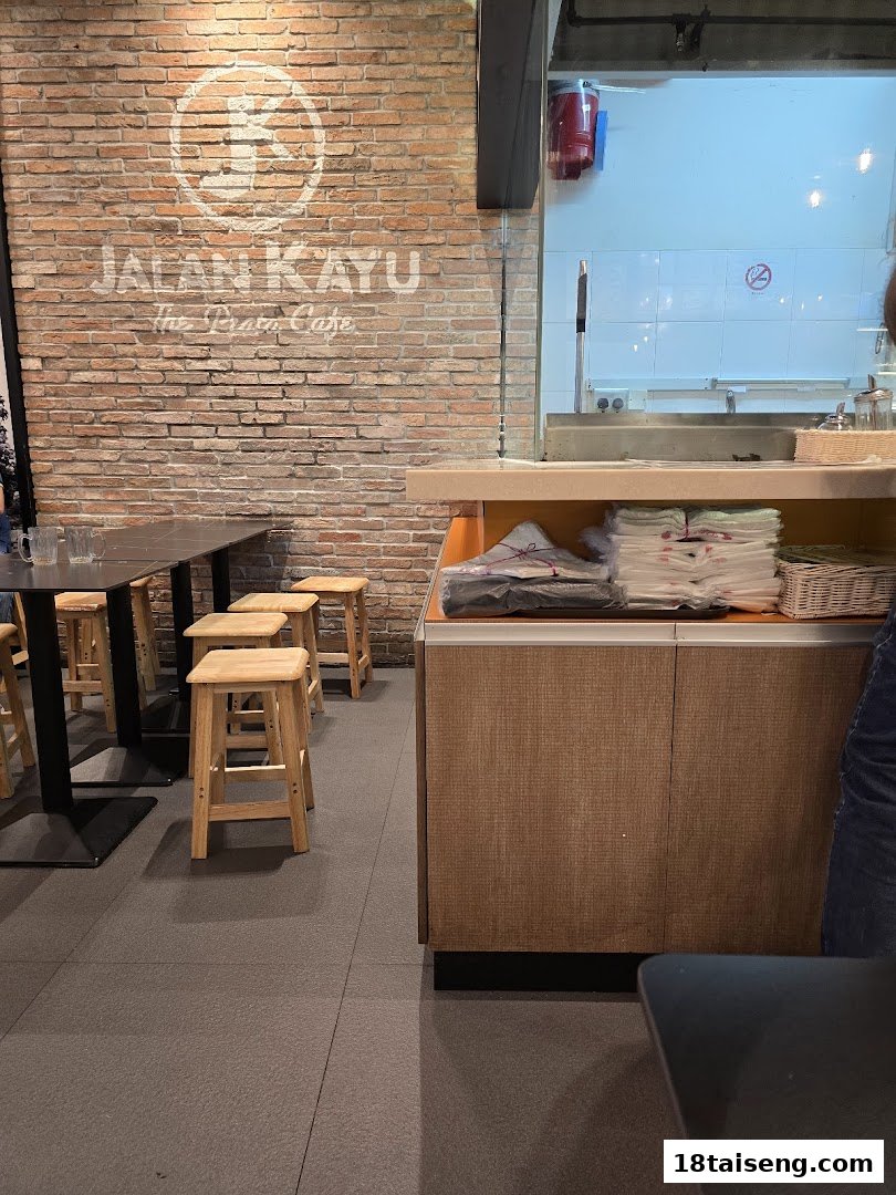 Interior view of Jalan Kayu The Prata Cafe showing seating, a counter, and a glimpse of the kitchen.