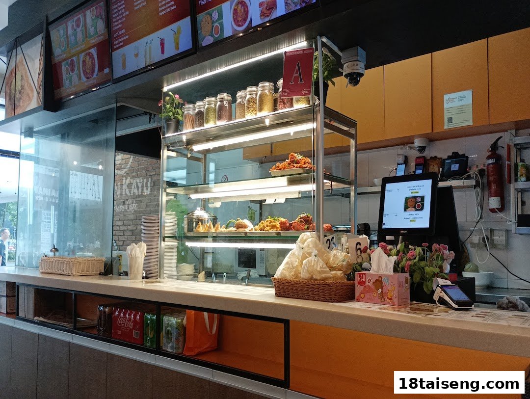 Interior view of Jalan Kayu The Prata Cafe counter with food display, digital menus, and POS system.