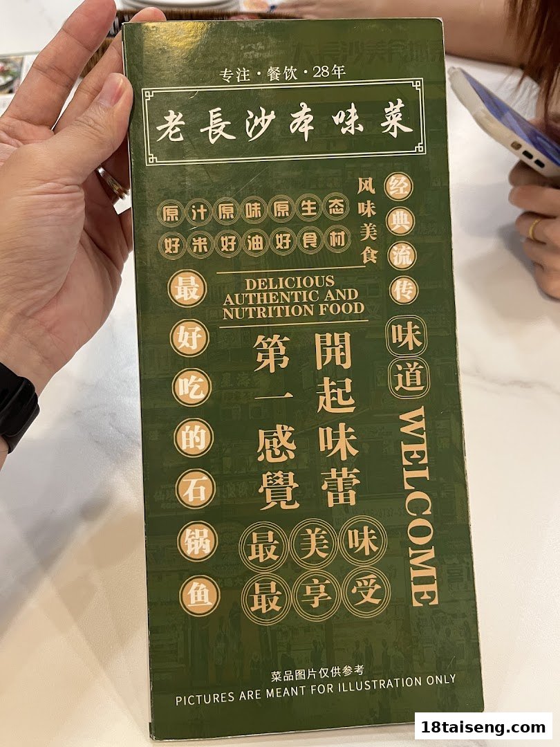 A hand holds a green menu cover for Lao Chang Sha restaurant, featuring slogans and a highlighted dish.