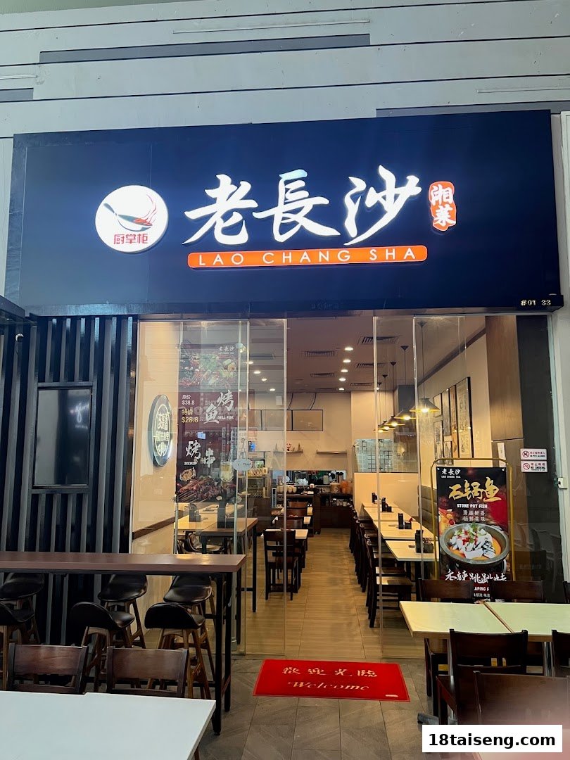 The illuminated shop front of Lao Chang Sha restaurant, featuring its name and a glimpse of the inviting interior.
