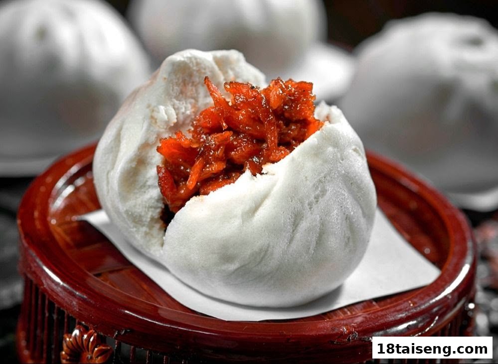 A close-up of a steamed bun (bao) filled with savory red char siu pork, on a wooden tray.