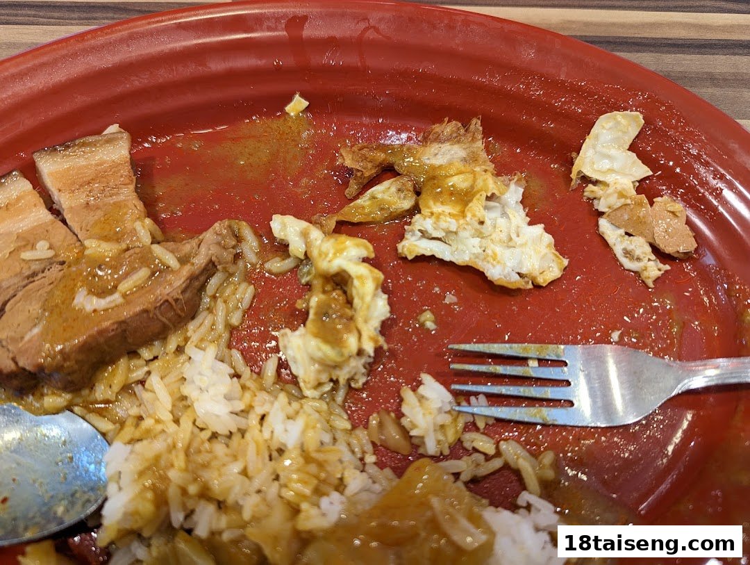 A close-up of a partially eaten meal on a red plate, featuring rice, meat, and sauce.
