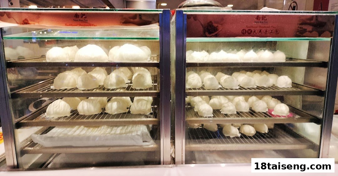 Two glass display cases showcasing numerous freshly steamed white buns.