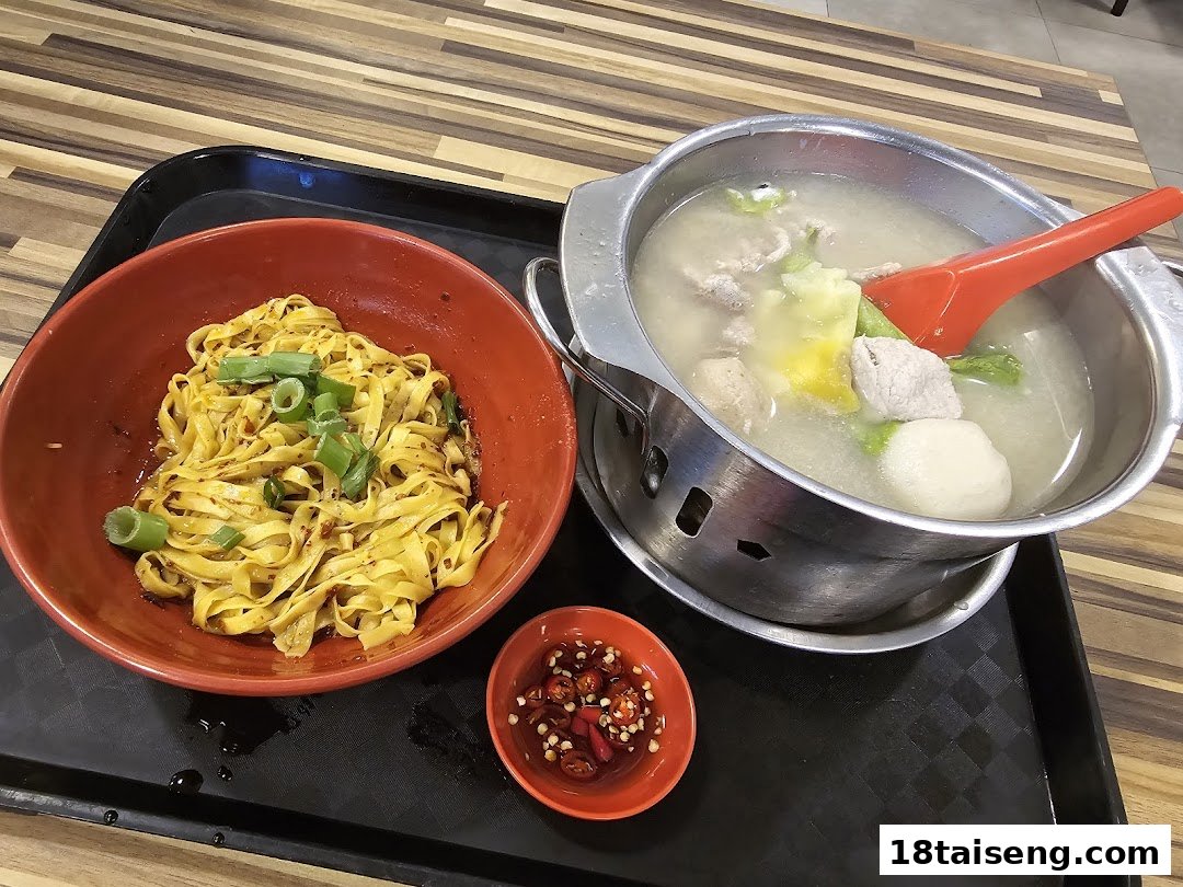 A tray with a bowl of seasoned noodles, a pot of hearty soup, and a small dish of chili.