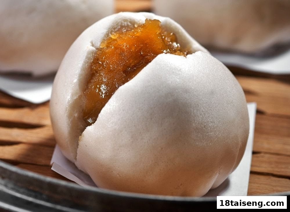 A close-up of a fluffy steamed bun with a rich, golden-brown sweet filling.