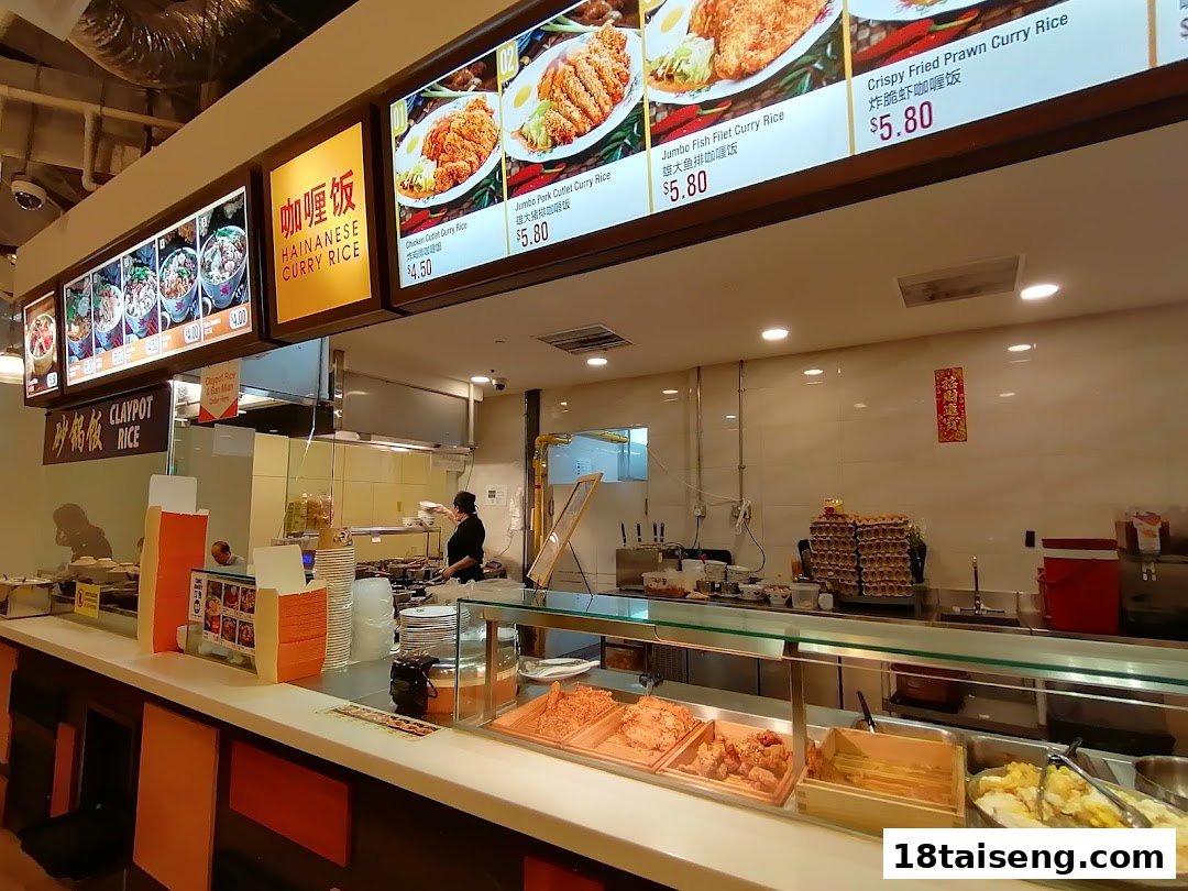 An interior view of a food stall with digital menu boards and a chef preparing food.