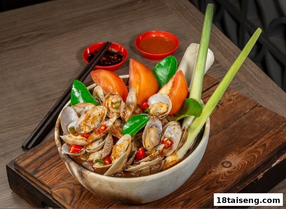 A vibrant bowl of spicy clams with tomatoes, herbs, and dipping sauces on a wooden surface.
