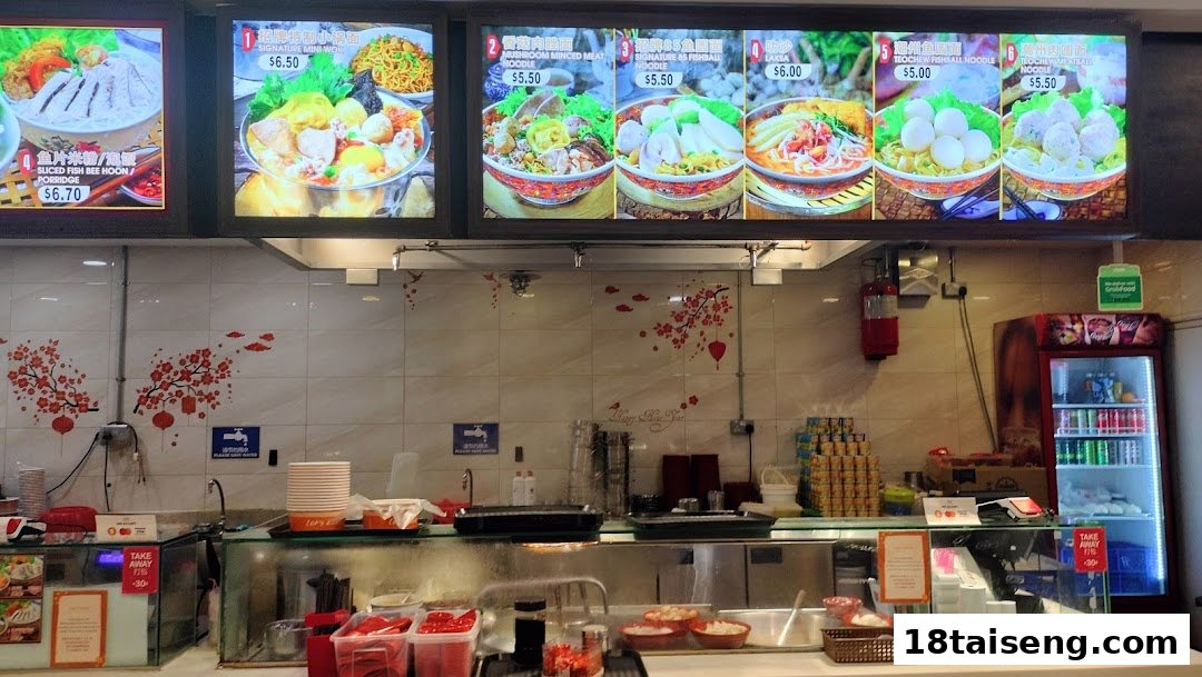 A food stall counter with an illuminated menu board displaying various noodle and porridge dishes.