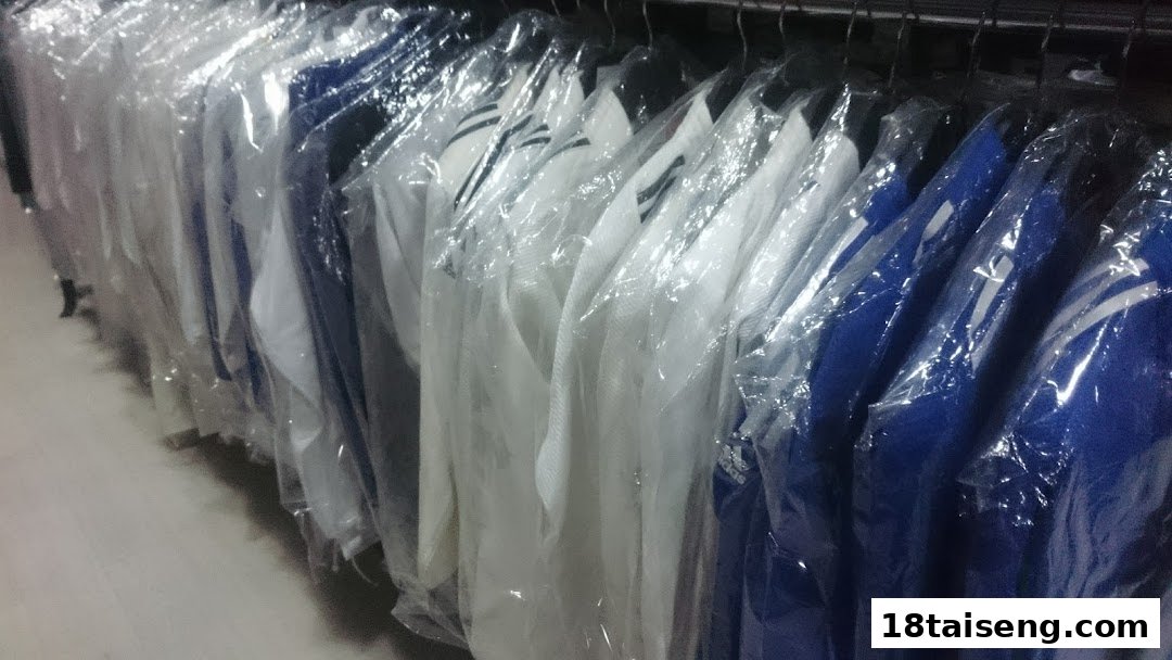 A rack of sports apparel, including white and blue shirts, individually wrapped in plastic.