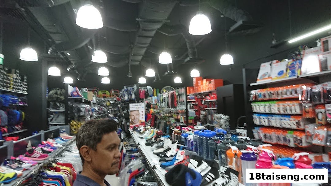 Interior view of Liang Seng Sports, showcasing athletic footwear, apparel, and accessories with a customer browsing.