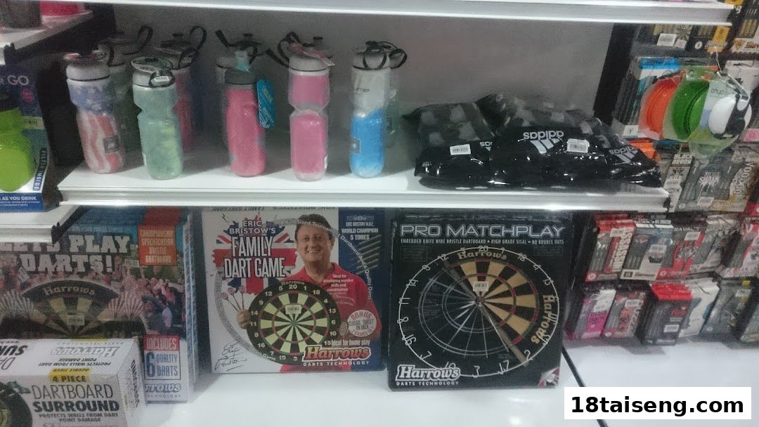 A retail shelf displaying various sports equipment including water bottles, Adidas bags, and dartboards.