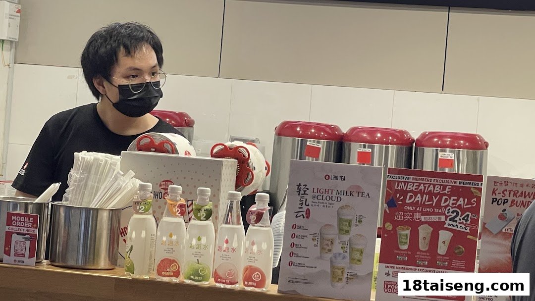 A staff member at the LiHO TEA counter with various drinks and promotional displays.