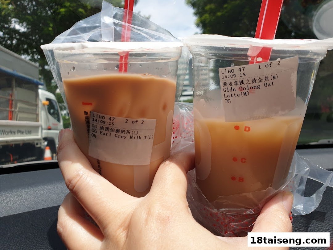 Two hands holding two refreshing LiHO TEA bubble tea drinks with visible order labels.