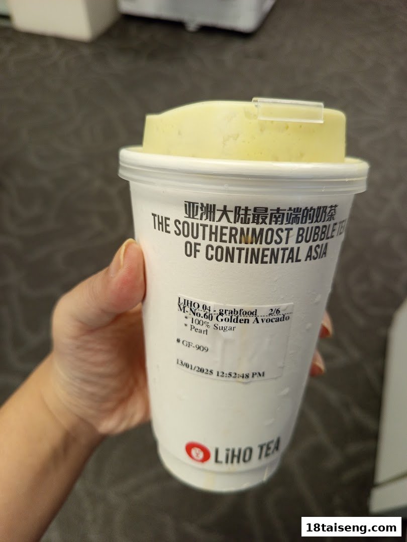 A hand holds a LiHO TEA cup featuring the Golden Avocado bubble tea.
