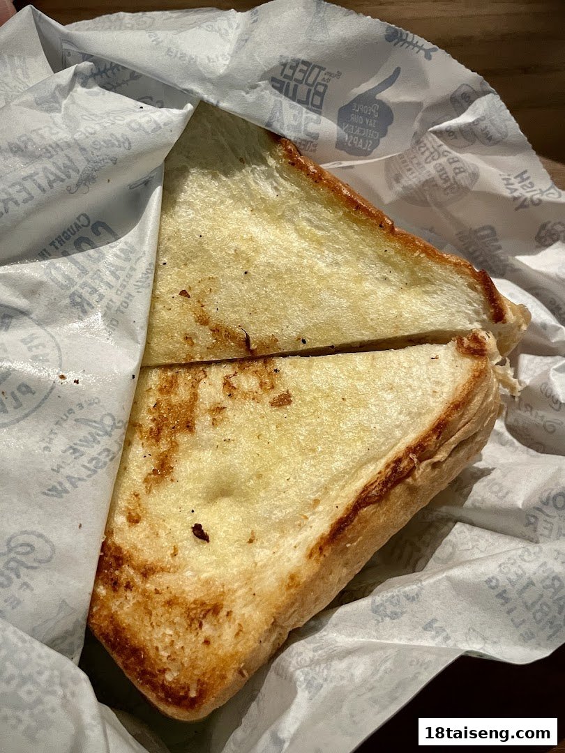 A golden-brown toasted bread slice, likely a side, wrapped in Long John Silver's branded paper.