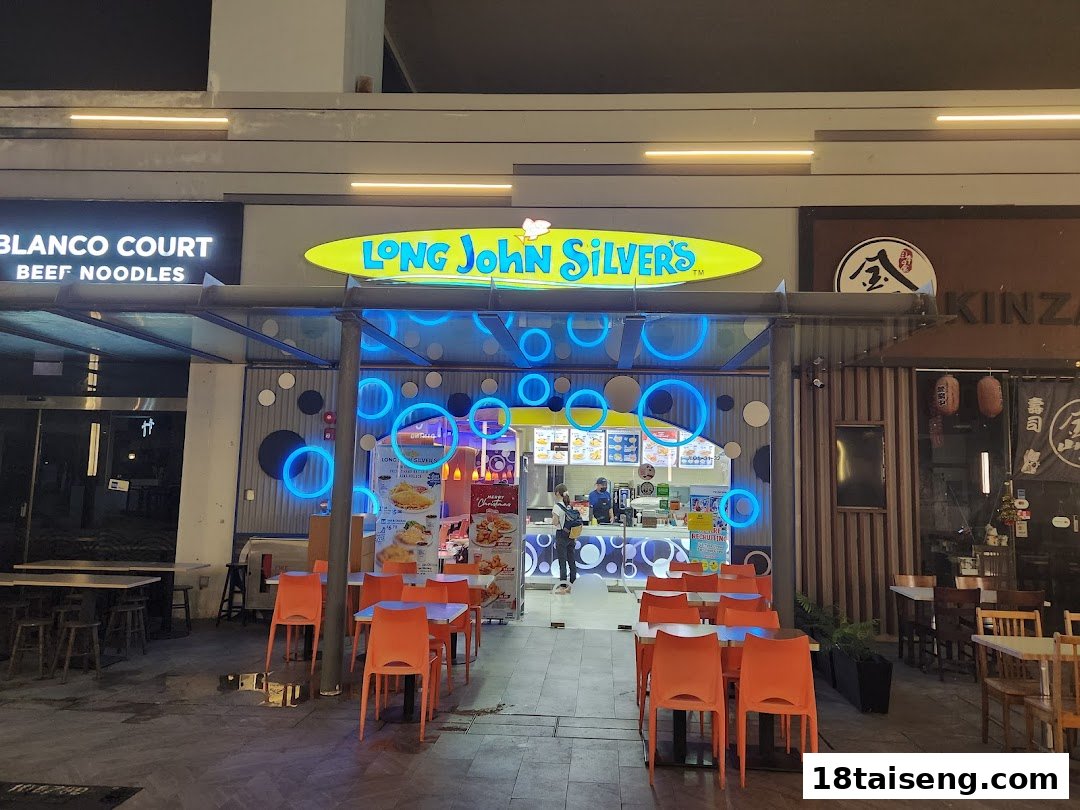 The illuminated entrance of Long John Silver's with outdoor seating and blue neon accents.