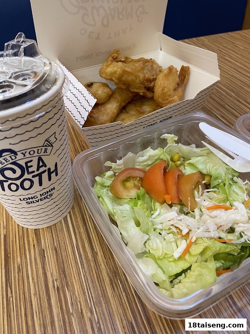 A meal from Long John Silver's featuring fried seafood, a fresh salad, and a branded drink.