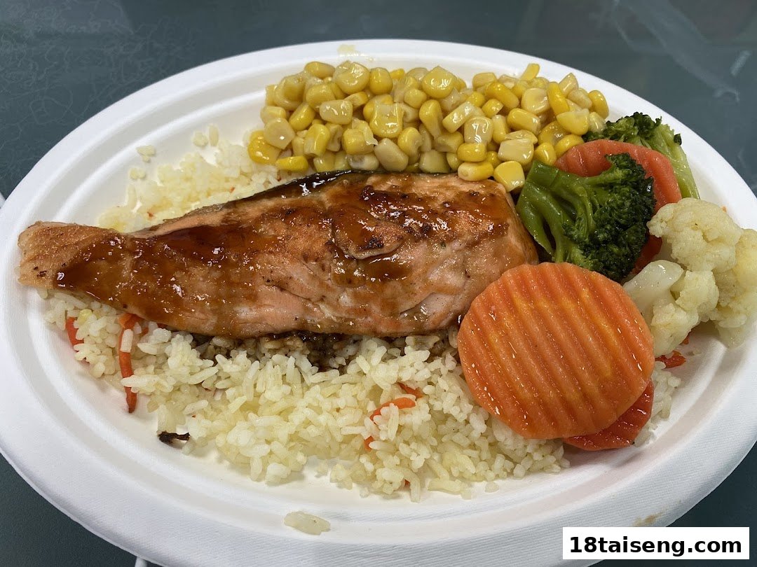 A delicious salmon fillet with rice, corn, and mixed vegetables on a white plate.