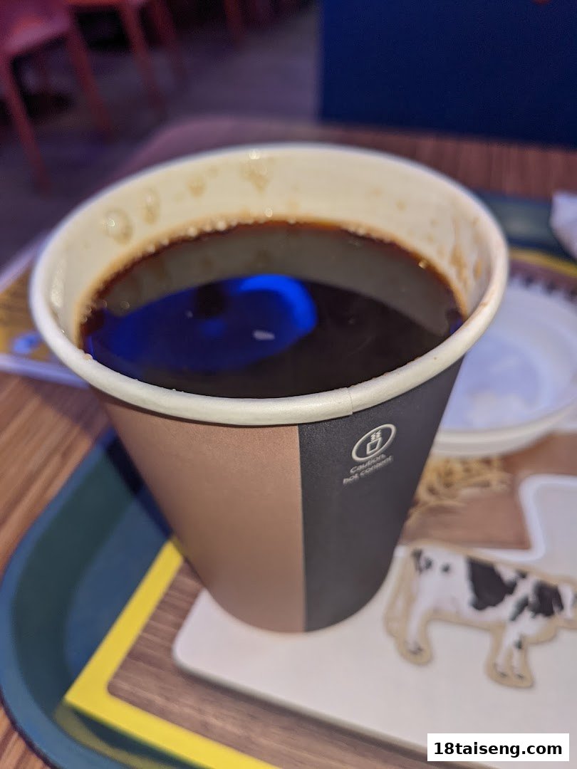 A close-up of a dark beverage in a paper cup on a tray.