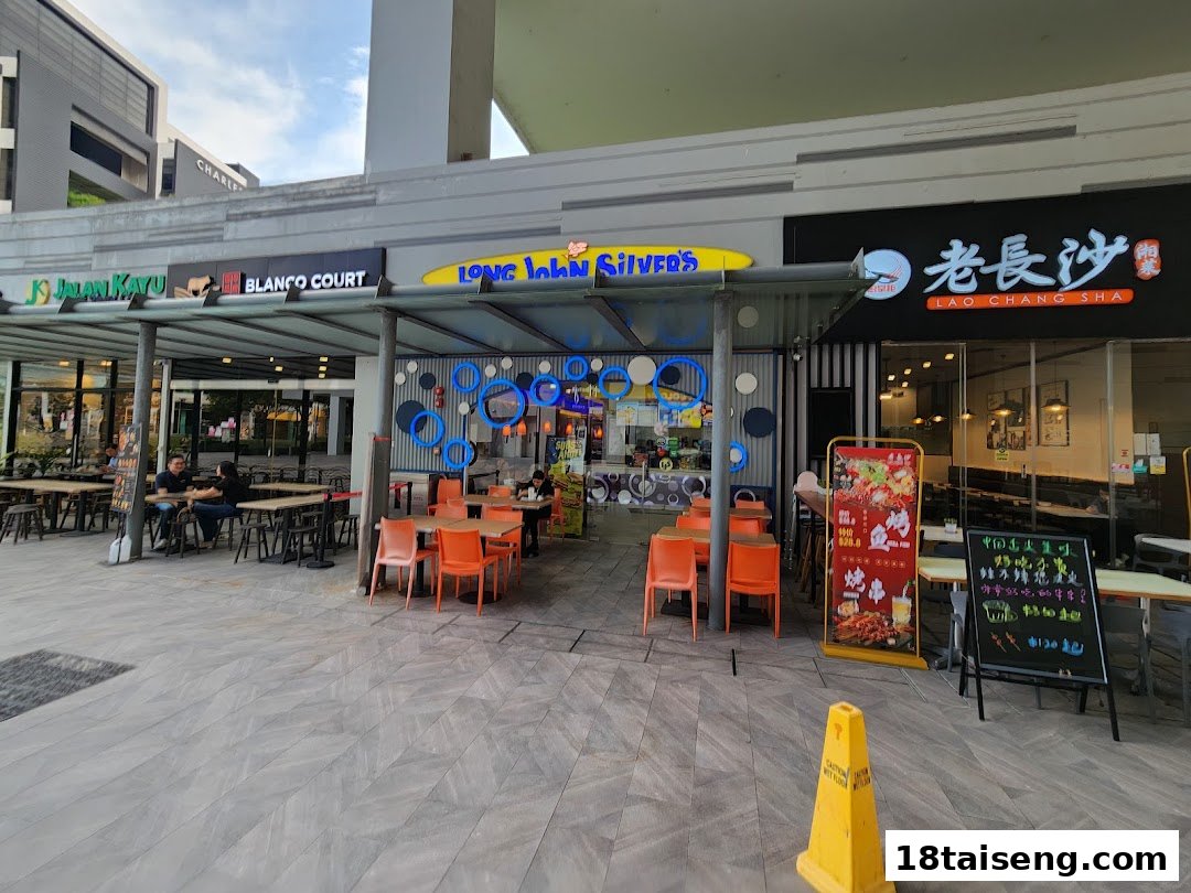 Exterior view of Long John Silver's fast-food restaurant with outdoor seating and neighboring shops.