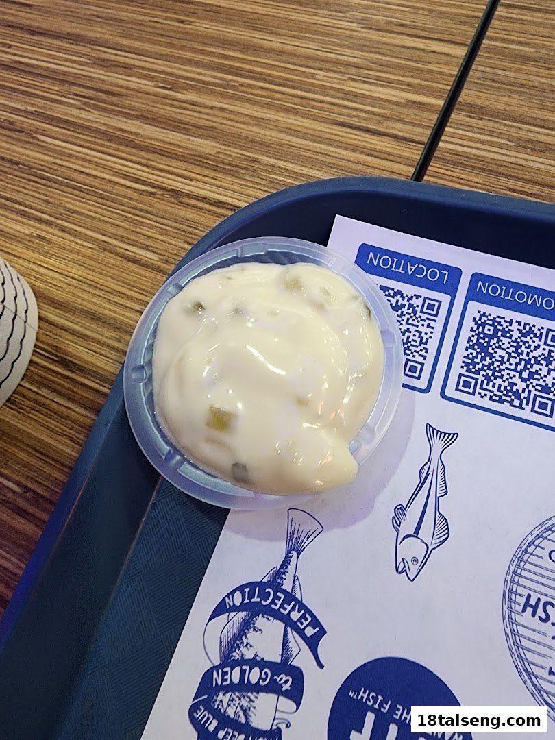 A small container of creamy tartar sauce on a branded tray liner at Long John Silver's.