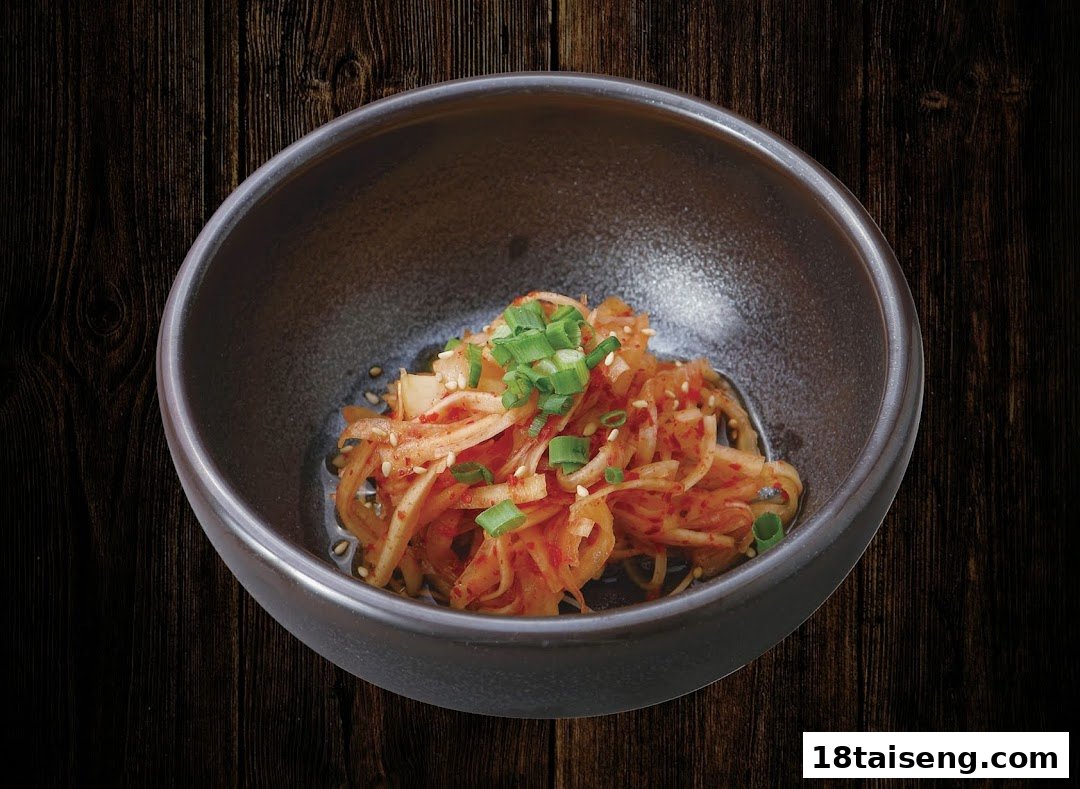 A bowl of spicy pickled radish or kimchi, garnished with green onions and sesame seeds.