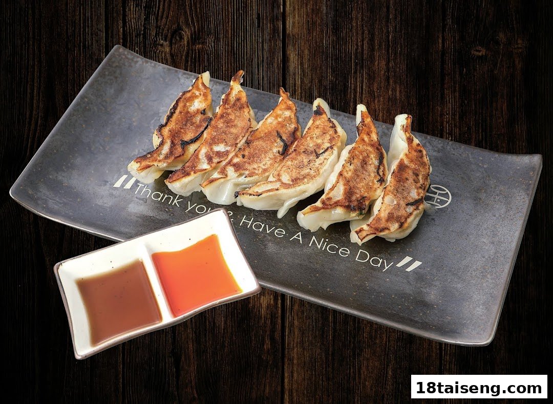 A plate of perfectly pan-fried gyoza with two dipping sauces on a dark wooden background.