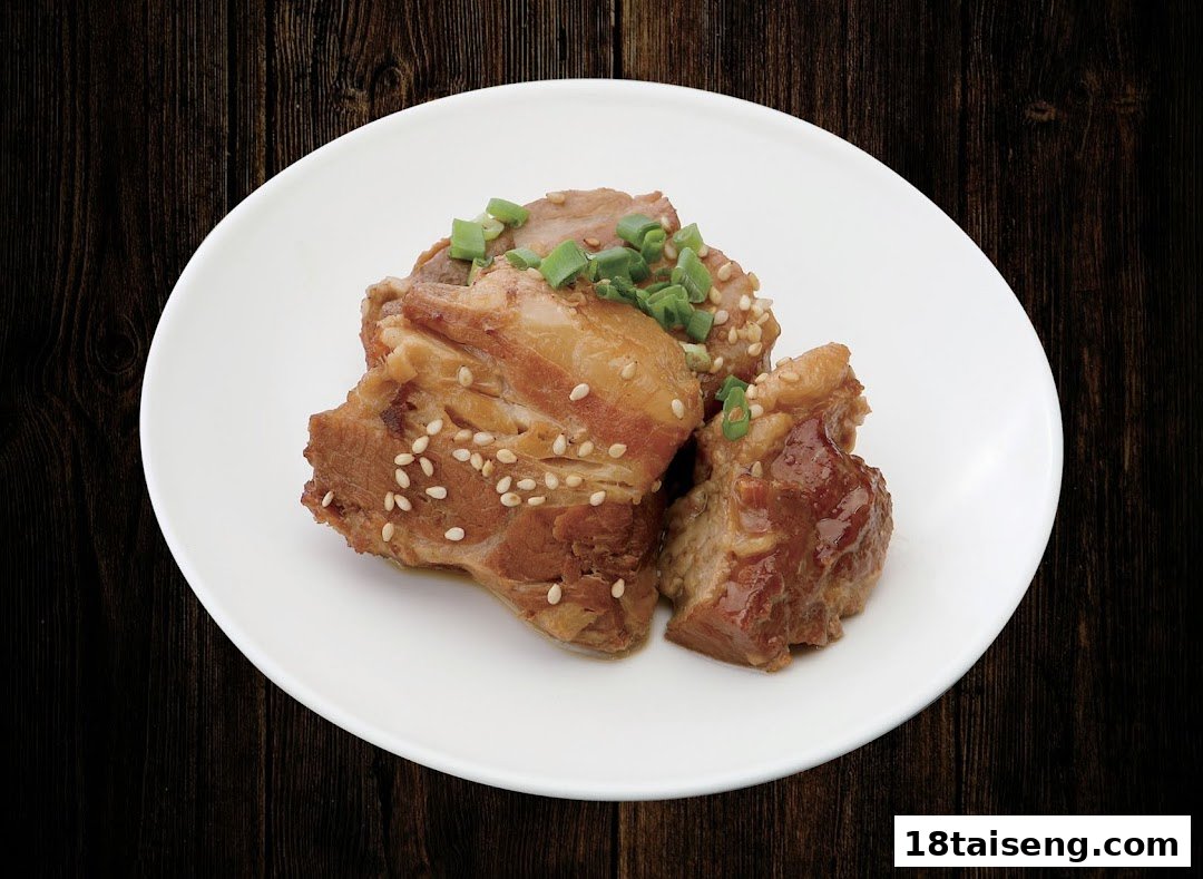 A white plate holds tender braised pork belly pieces, garnished with sesame seeds and green onions.