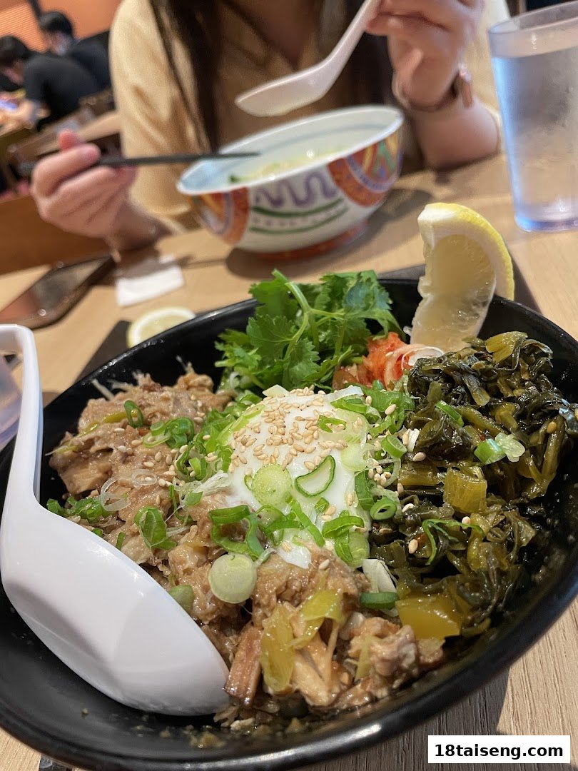 A close-up of a delicious ramen or rice bowl with various toppings, served in a vibrant restaurant setting.