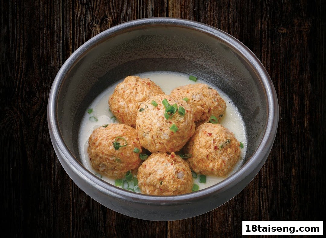 A bowl of savory meatballs in a creamy sauce, garnished with chopped green onions.