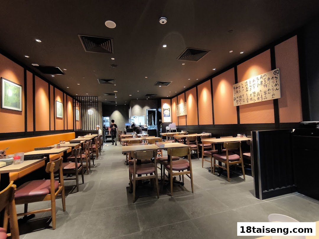 An inviting interior view of Marutama Ramen, featuring warm lighting, wooden tables, and comfortable seating.