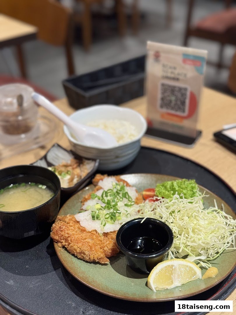 A delicious Japanese tonkatsu meal set with rice, miso soup, and salad on a table.