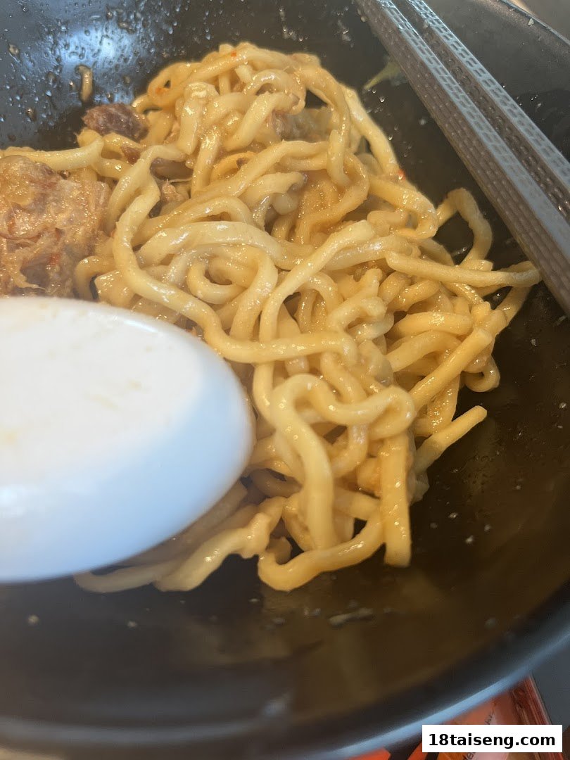 Close-up of delicious ramen noodles with meat in a black bowl, ready to be enjoyed.