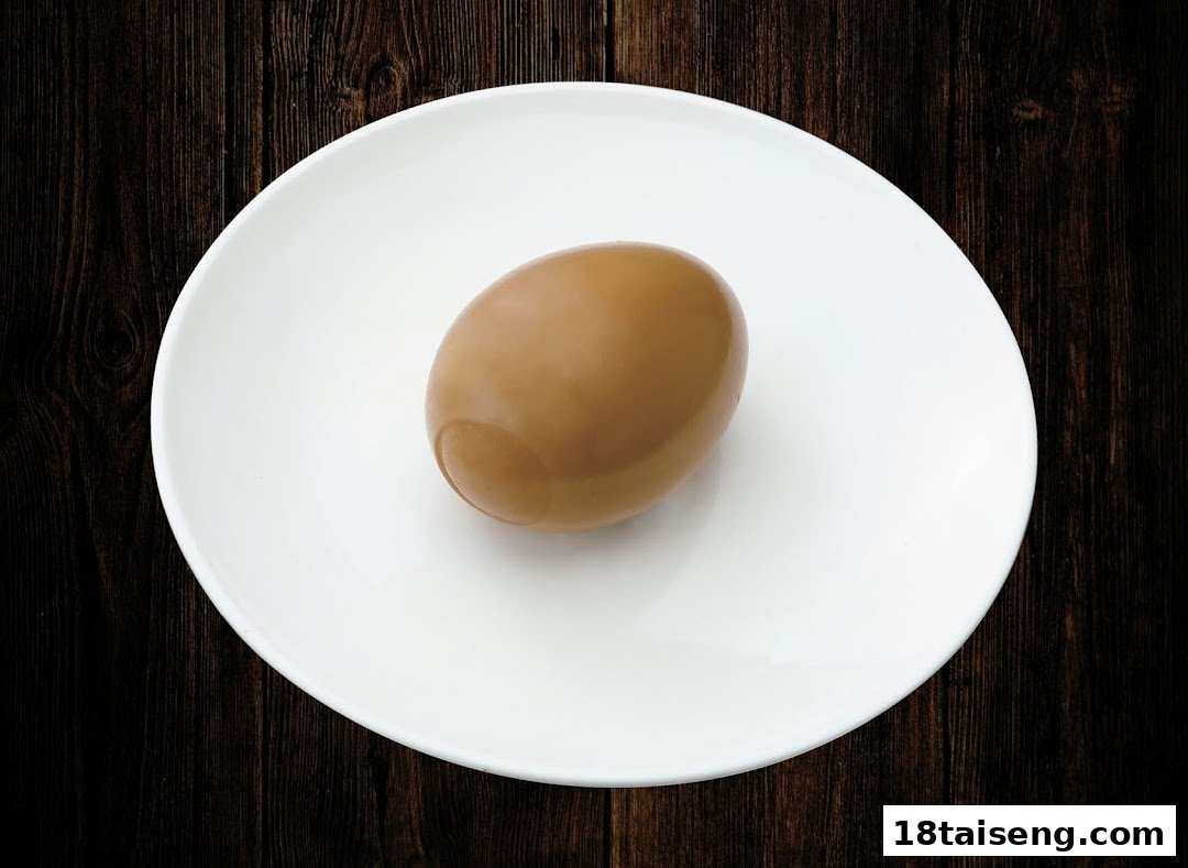 A perfectly cooked ramen egg (Ajitama) on a white plate, set against a dark wooden background.