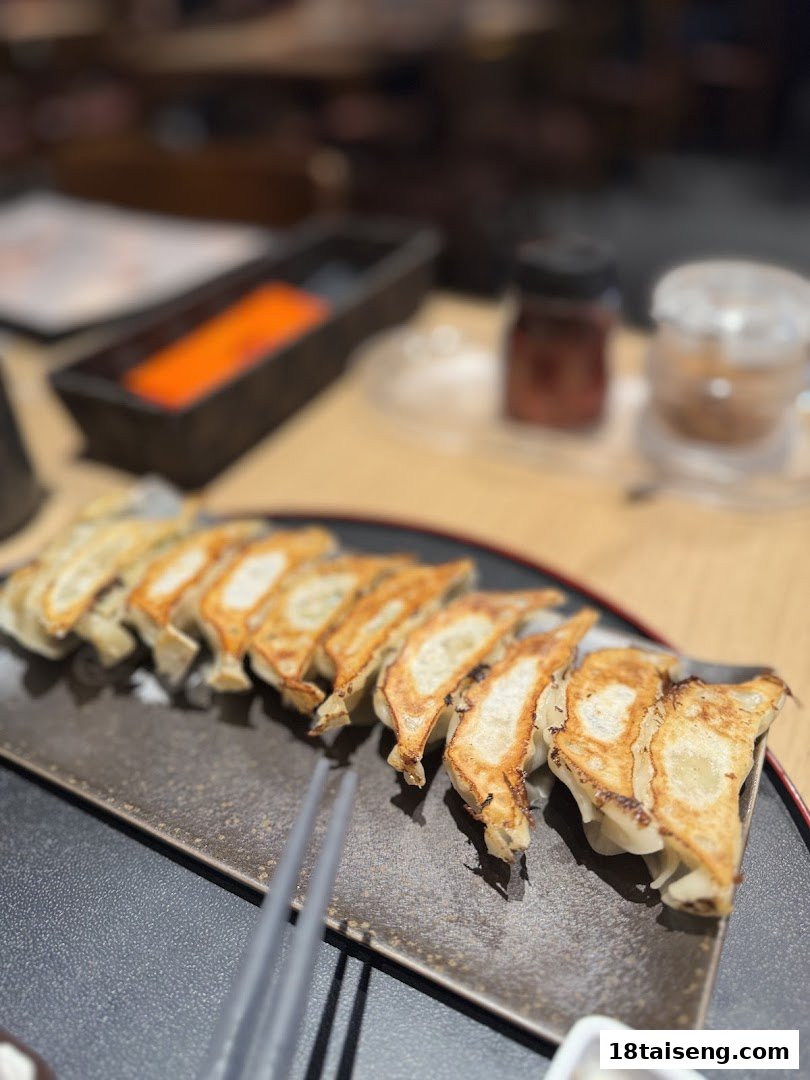 A plate of golden-brown gyoza served with chopsticks on a dark rectangular dish at Marutama Ramen.