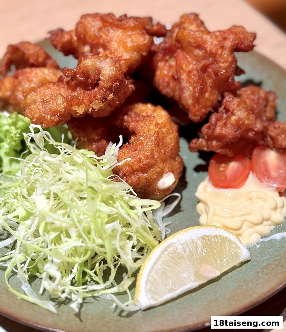 A plate of golden-brown fried chicken with shredded cabbage, lemon, and mayonnaise.