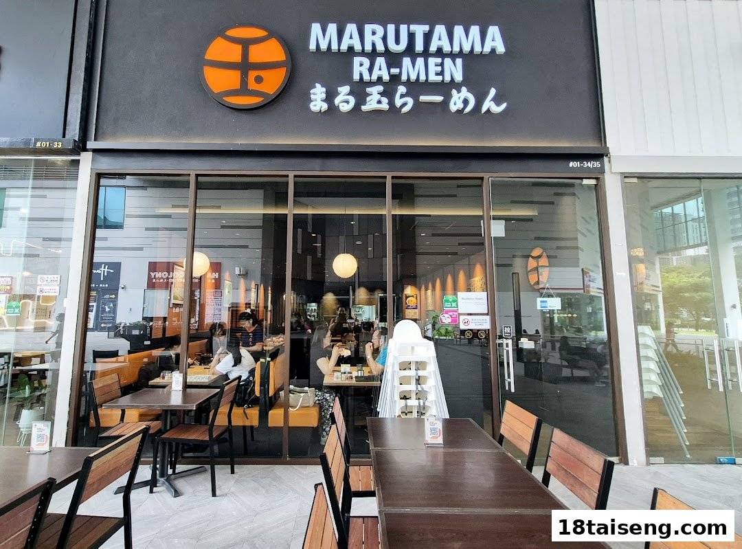 The storefront of Marutama Ramen Tai Seng, featuring its logo, signage, and visible interior dining area.