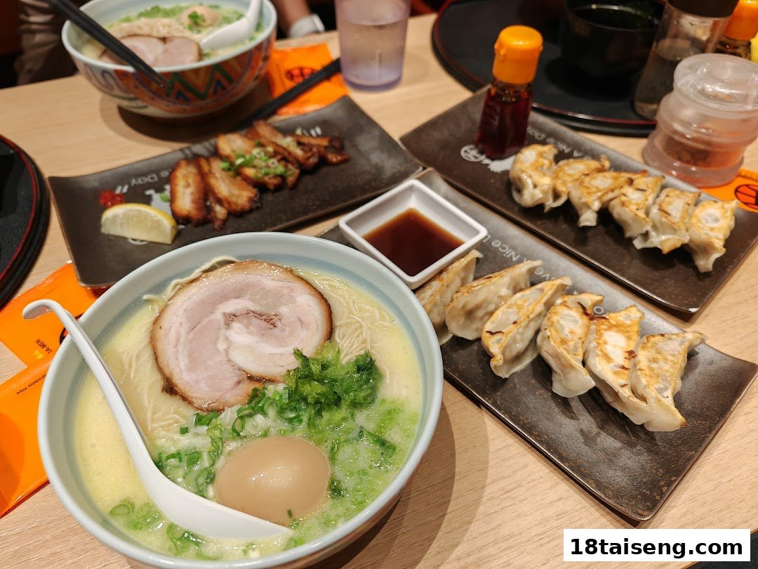 A table laden with two bowls of ramen, plates of gyoza, and grilled chashu pork at Marutama Ramen.