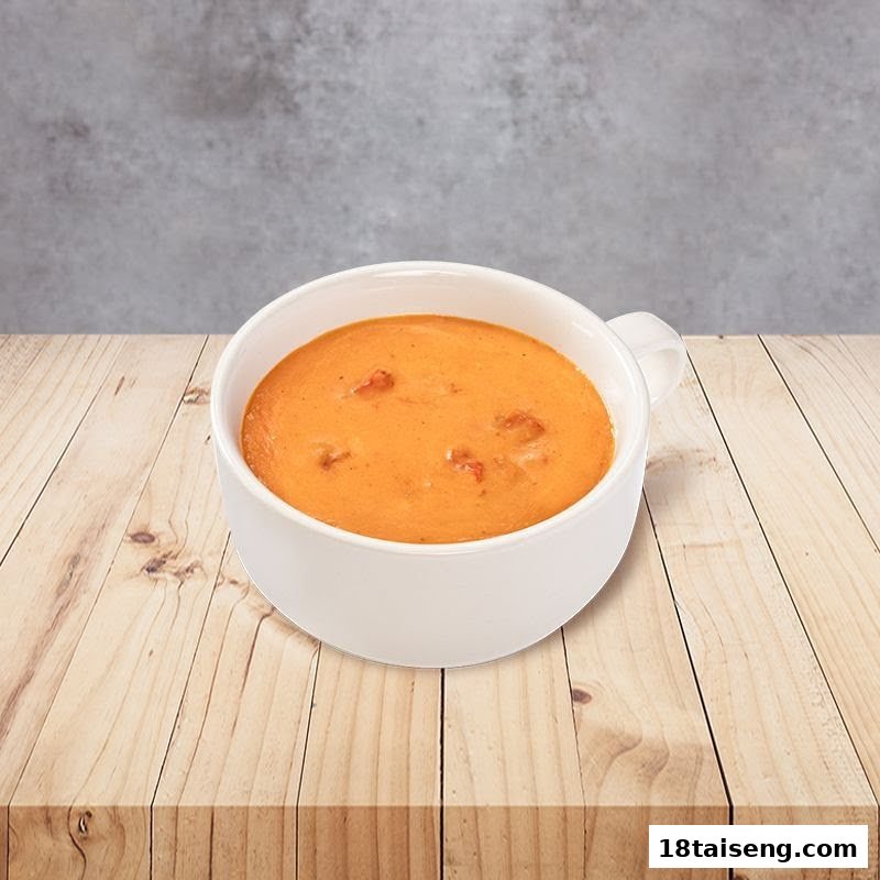 A white mug filled with a creamy orange soup, featuring small chunks, on a wooden table.