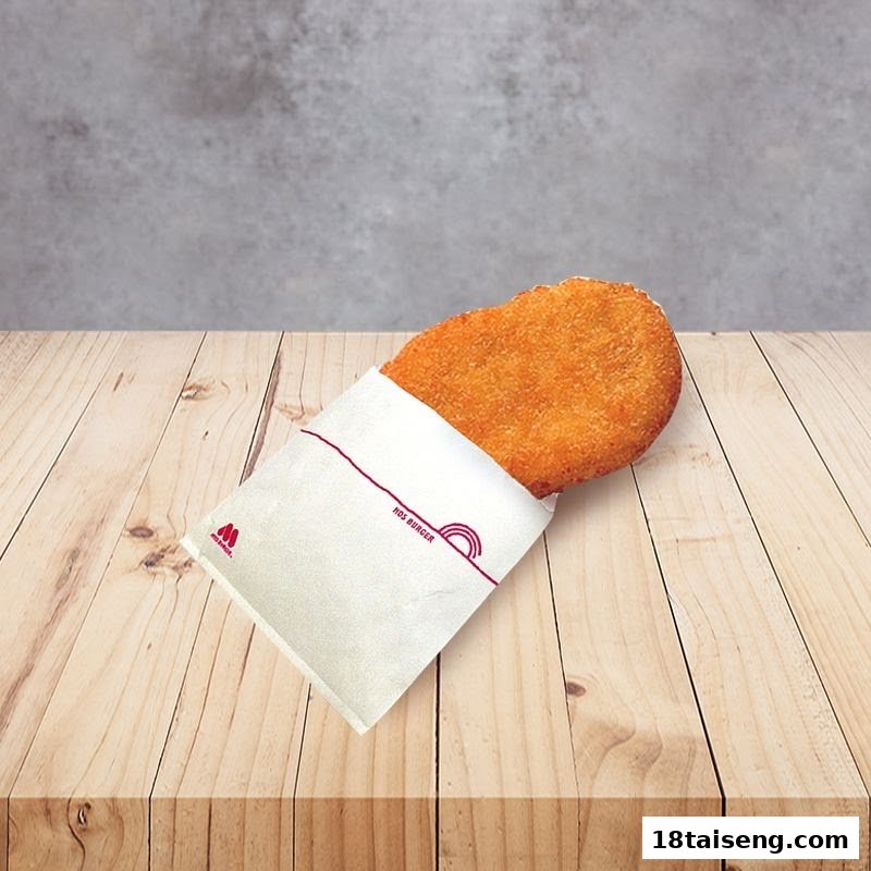 A crispy, golden-brown fried patty from MOS Burger, partially wrapped in its branded paper, resting on a wooden surface.