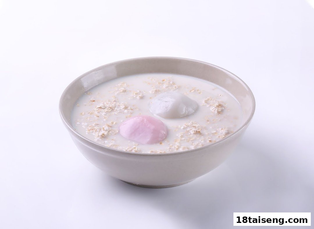 A bowl of milky oats with one pink and one white mochi-like dumpling.