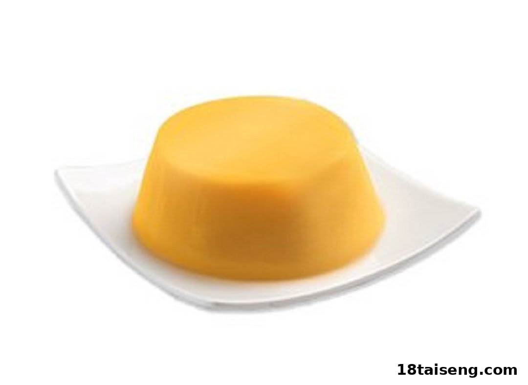 A vibrant yellow, dome-shaped pudding or dessert served on a white square plate.