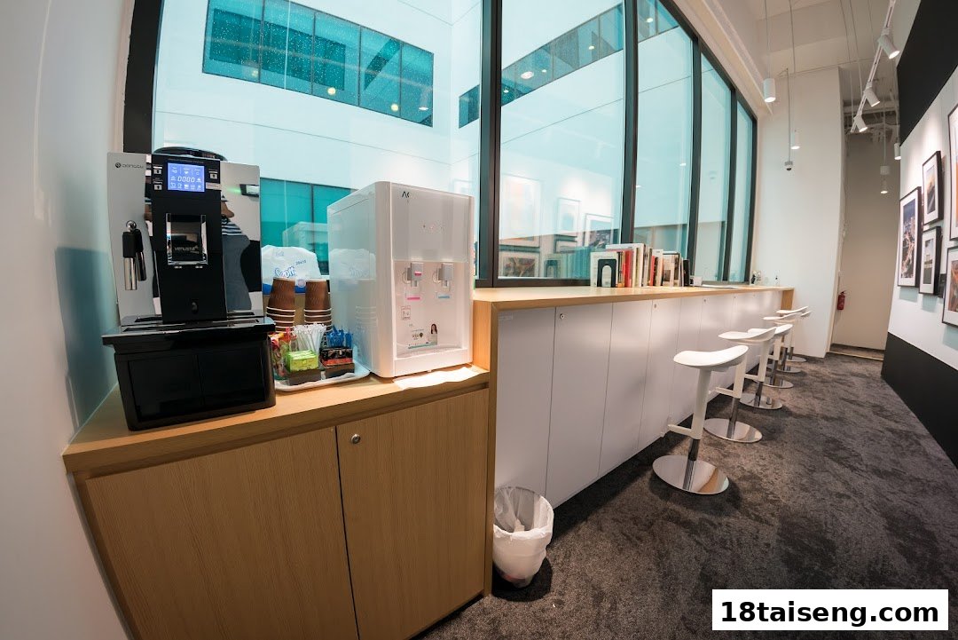 Modern lounge area at Nikon Singapore with coffee machine, water dispenser, and bar seating.