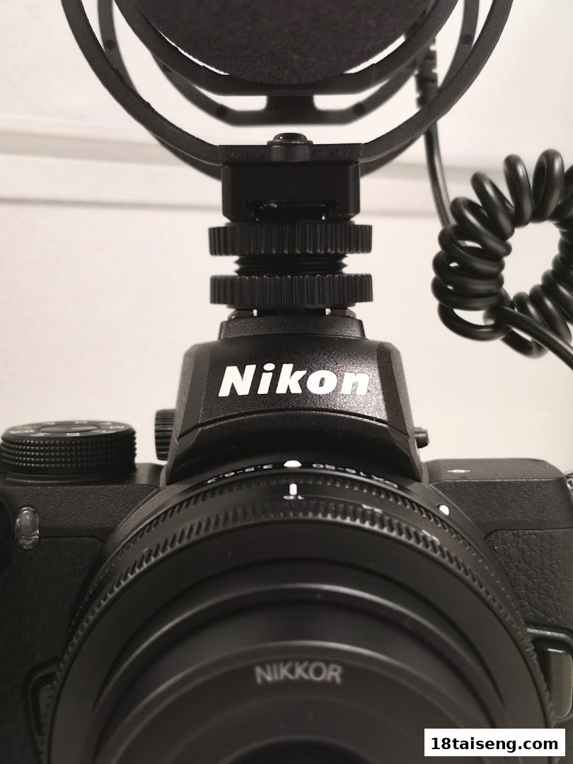 A close-up view of a black Nikon camera with a NIKKOR lens and an attached microphone.