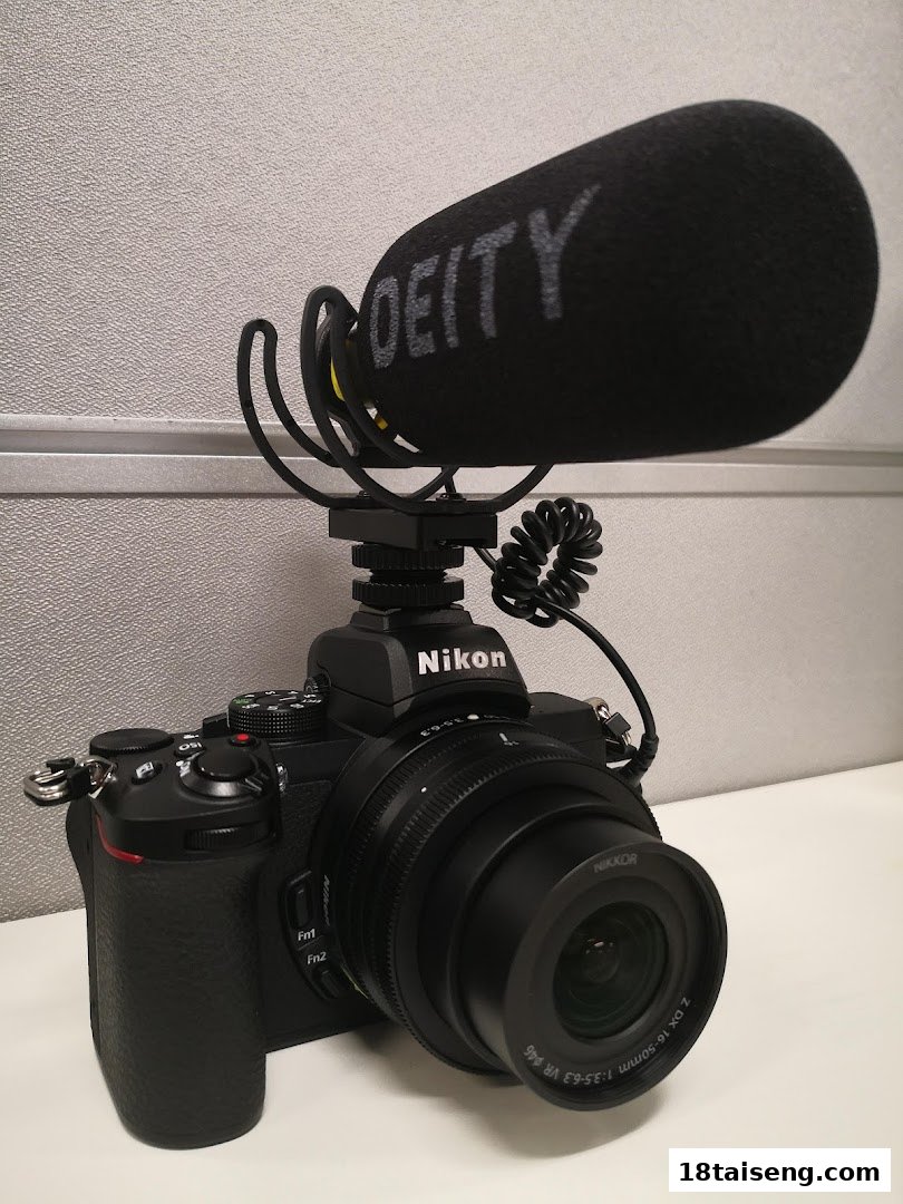 A black Nikon mirrorless camera with a Nikkor lens and a Deity shotgun microphone attached.