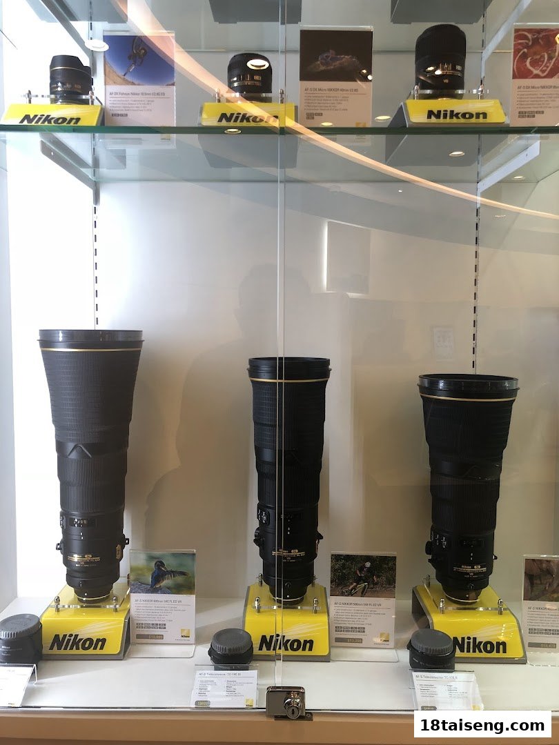 A display case showcasing various Nikon camera lenses, including large telephoto and micro lenses.