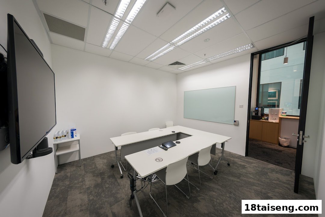 A modern, well-lit meeting or training room with a large screen, U-shaped table, and whiteboard.