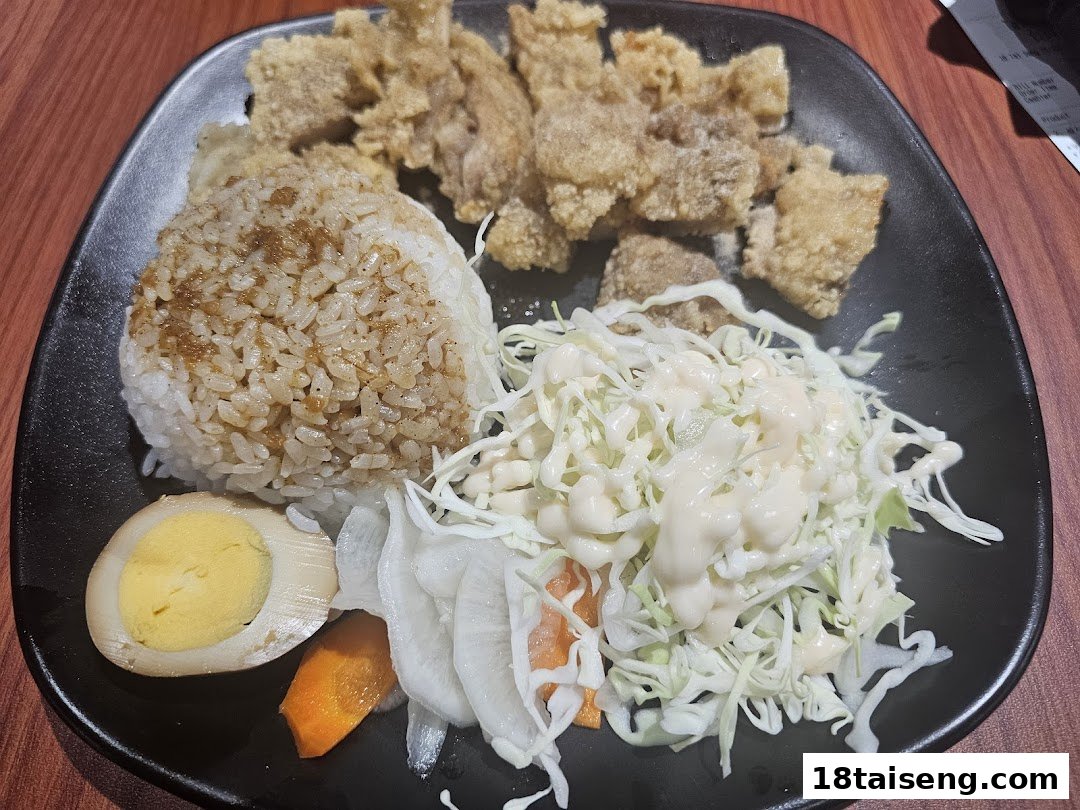 A plate of Taiwanese fried chicken, seasoned rice, cabbage salad, pickled vegetables, and a braised egg.