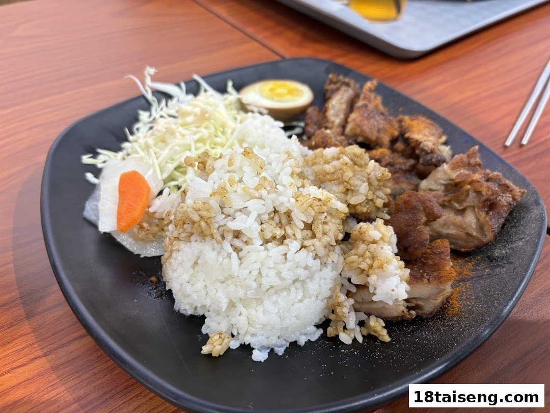 A plate of Taiwanese fried chicken with seasoned rice, shredded cabbage, and a boiled egg.